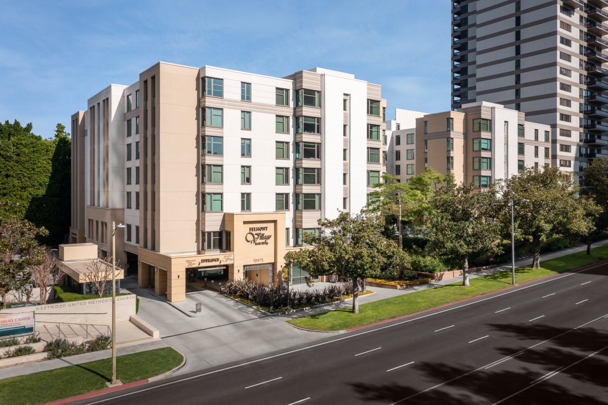 A modern hotel building situated in an urban environment with surrounding trees and a main road.