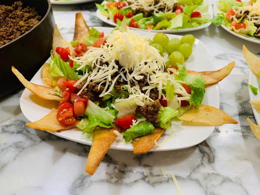 A fresh salad with cherry tomatoes, lettuce, and cheese garnished with grapes and bread slices.