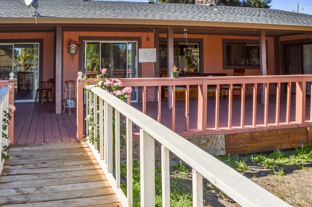 A wooden ramp leading to a cozy house with a spacious porch.