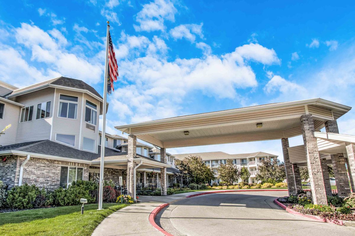 A retirement home with a covered entrance and an American flag on display.