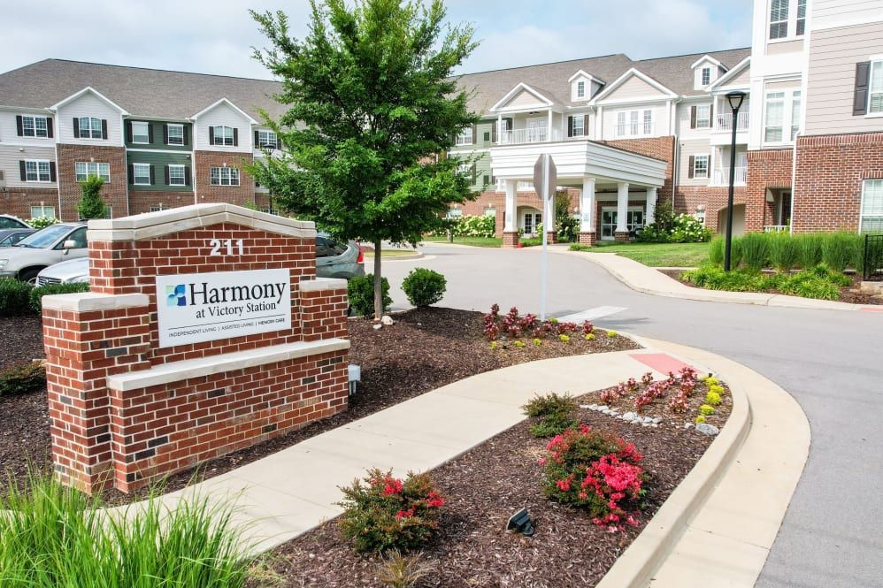 A well-maintained building entrance with landscaped gardens and a visible sign.