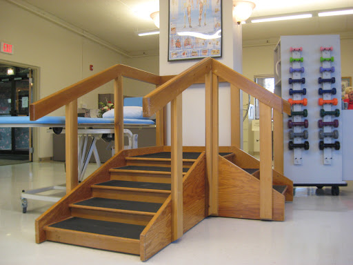 A wooden staircase designed for rehabilitation and therapy, featuring handrails and non-slip surfaces.
