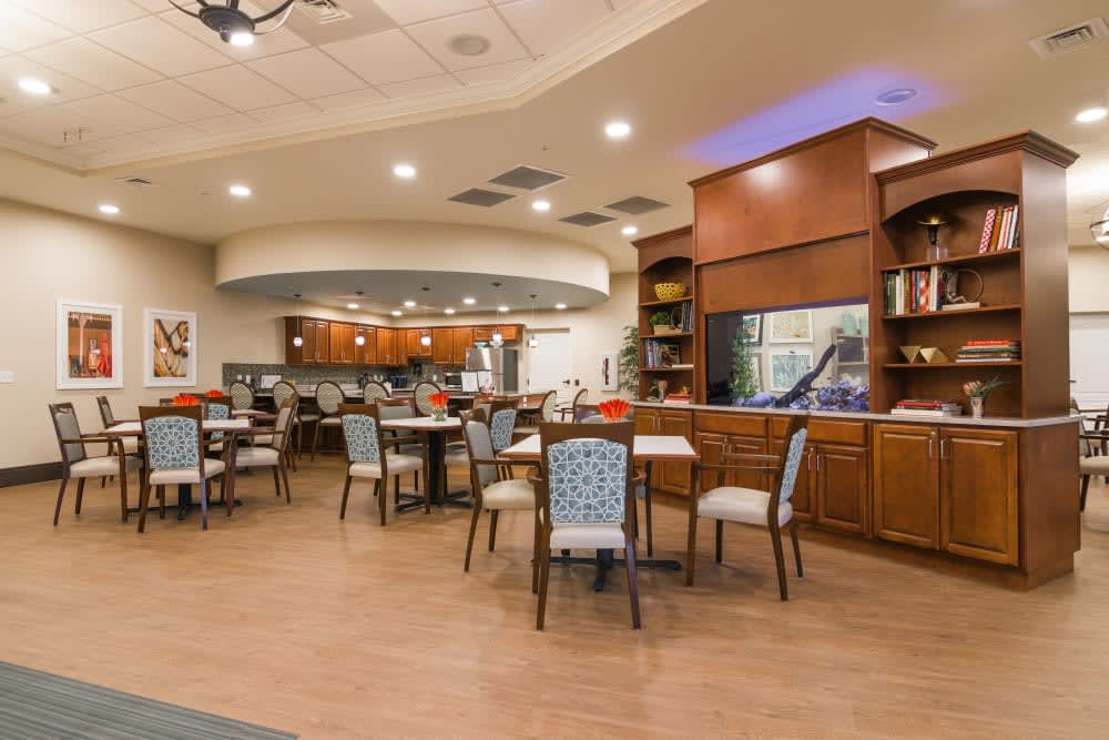 A modern dining area featuring a bar counter, tables, and chairs arranged under warm indoor lighting.