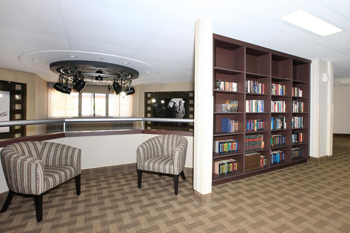 A cozy library corner with bookshelves and two striped chairs.