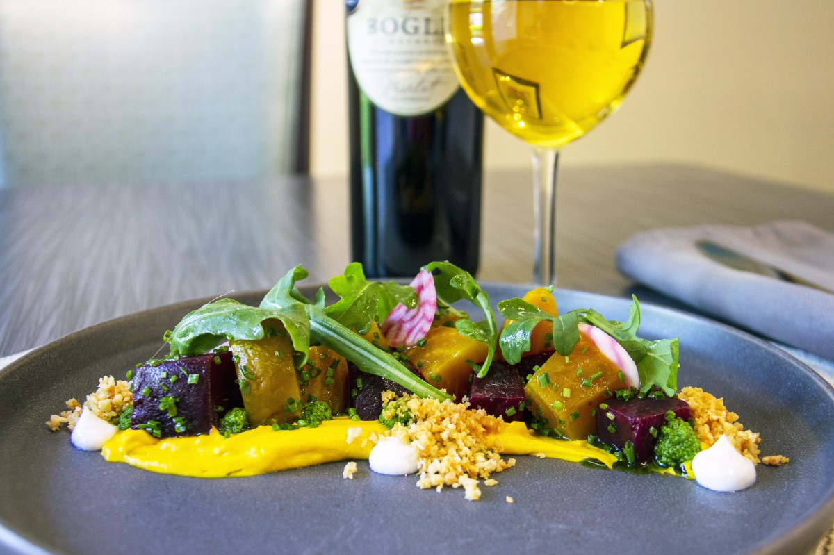 A beautifully plated gourmet salad featuring beets, arugula, and a wine pairing.