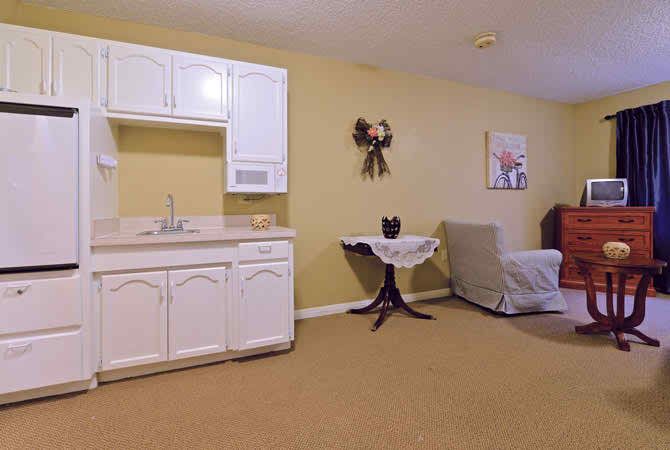 A cozy studio apartment with a small kitchenette and simple furnishings.