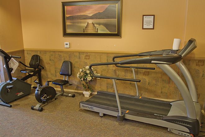 A small fitness room with a treadmill, stationary bike, and wall decorations.
