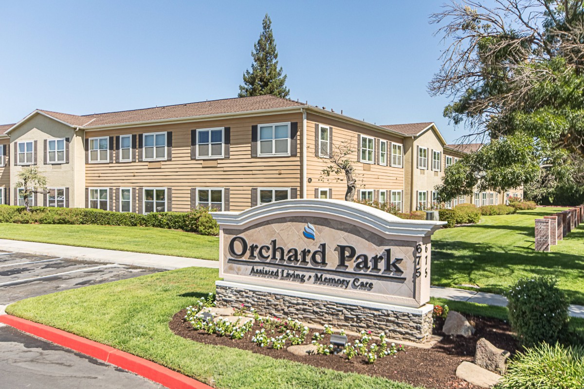 Orchard Park senior living community entrance with a visible sign and well-maintained landscape.