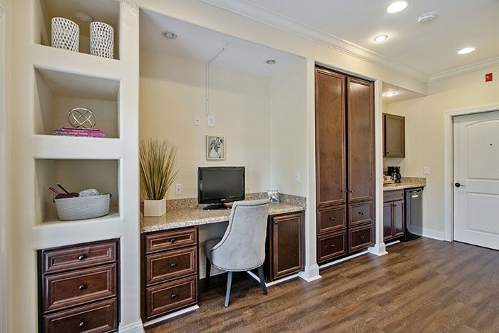 A modern home office space with built-in desk, computer, and shelving.