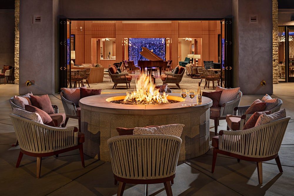 A cozy lounge area featuring a central fireplace surrounded by comfortable chairs, creating a warm and inviting atmosphere.