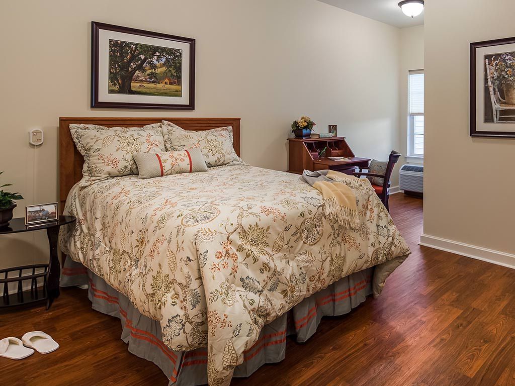 Cozy bedroom with floral bedding and wooden flooring.