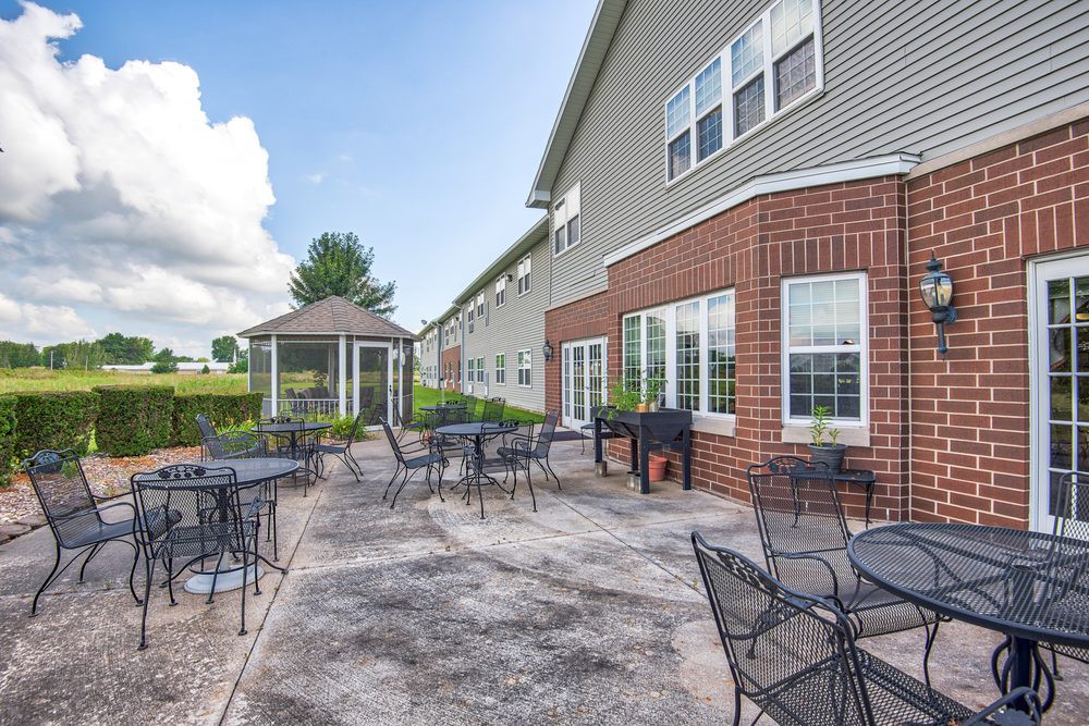 An outdoor patio area with tables, chairs, and a gazebo adjacent to a building.