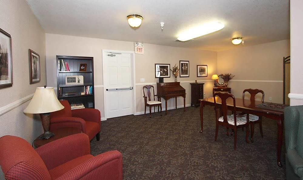 A cozy living room featuring a piano, bookshelves, and comfortable seating.