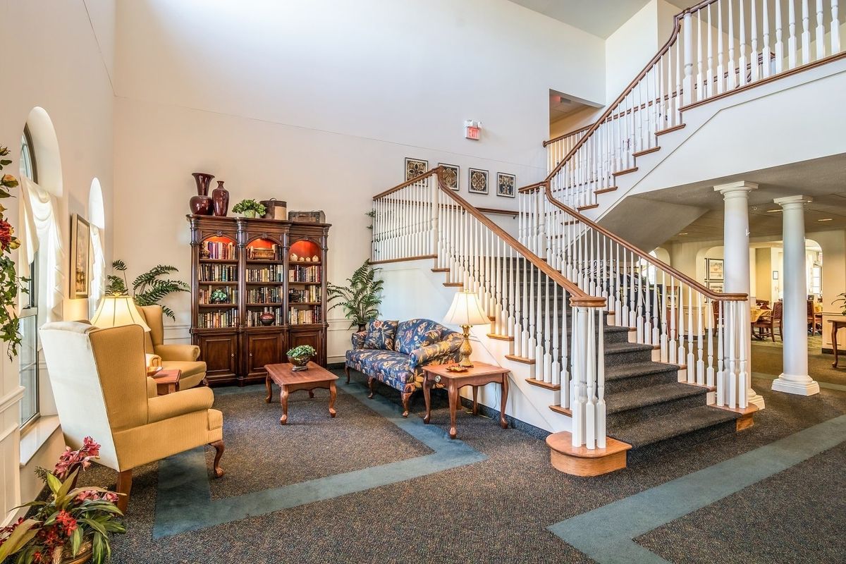 A cozy lobby space featuring a grand staircase, comfortable seating, and elegant decor.
