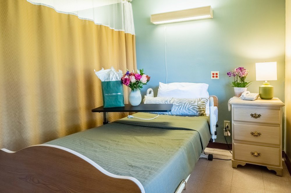 A neatly arranged hospital room with a bed and flowers on the table.