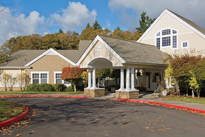 A picturesque residential building with a covered entrance and autumn foliage.