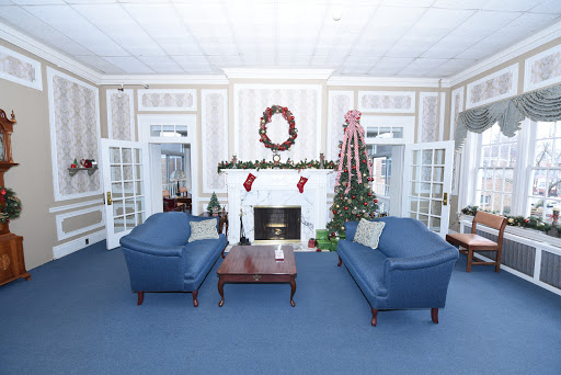A cozy living room beautifully decorated for the Christmas season, featuring blue sofas and a festive fireplace.