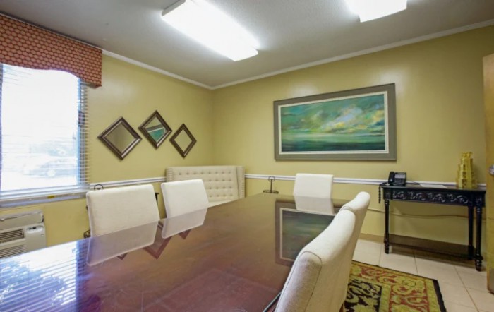 A modern conference room featuring a large table, white chairs, and decorative artwork on the walls.