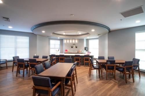 A modern dining area with multiple tables and chairs, featuring a wooden floor and stylish lighting.