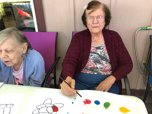 An elderly woman focused on her painting while engaging in a creative activity.