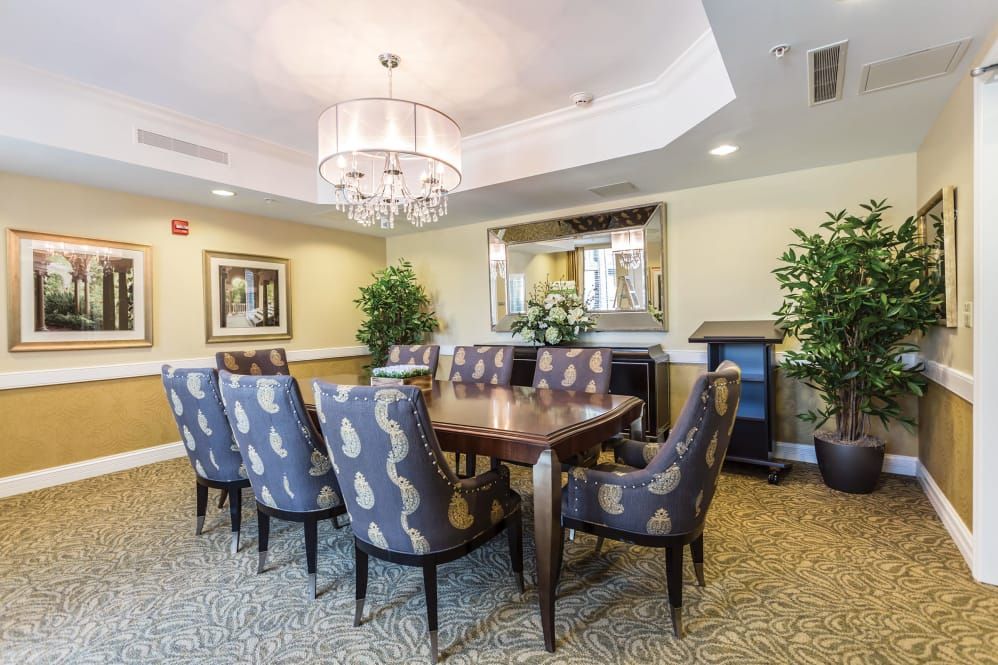 Elegant dining room with a large table, patterned chairs, and a chandelier.