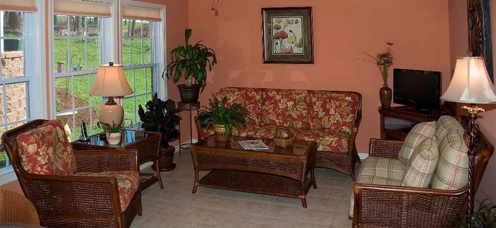 A cozy living room with a floral-patterned sofa, coffee table, and lush green plants.