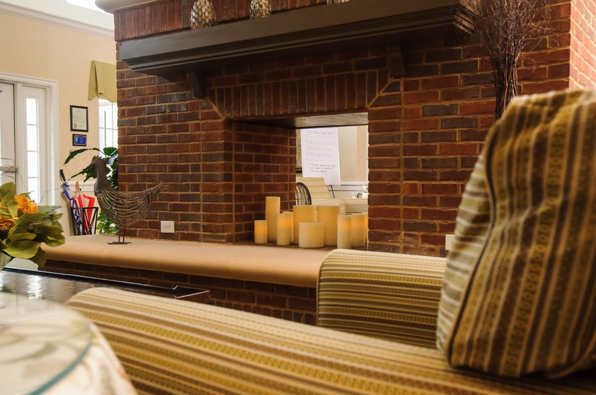 A cozy living room with a brick fireplace and glowing candles on the mantle.