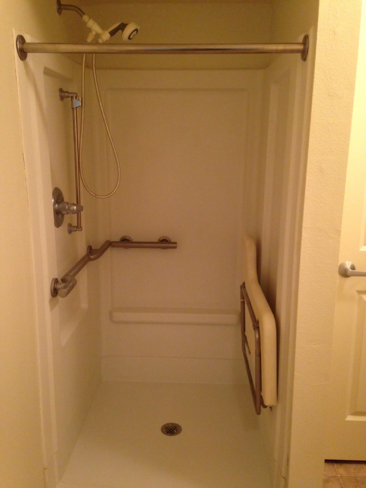Accessible shower with grab bars and a folding seat.