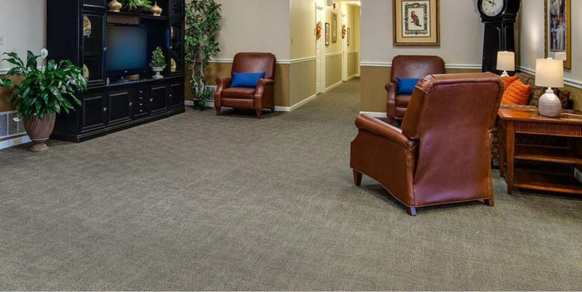 A quiet lobby area featuring leather chairs and a carpeted floor with a hallway in the background.