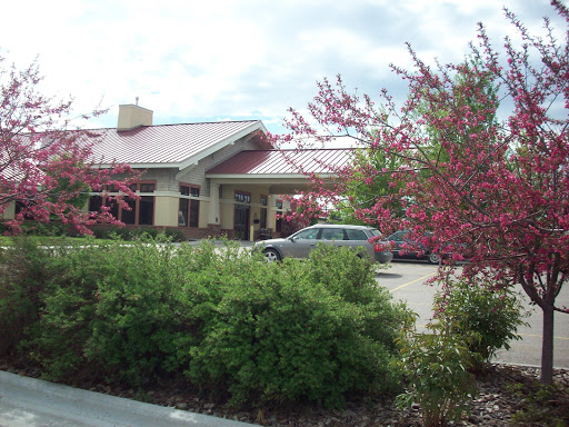 A restaurant building surrounded by blooming shrubs under a cloudy sky.