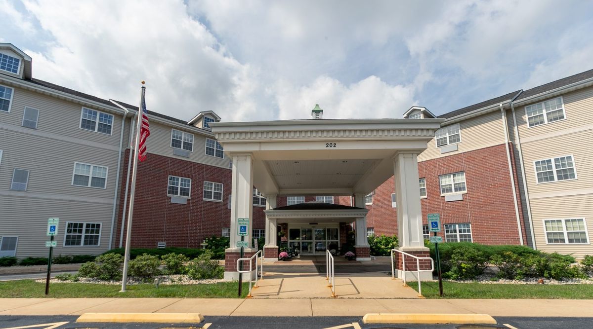 The entrance of a brick building with a covered walkway and an American flag nearby.