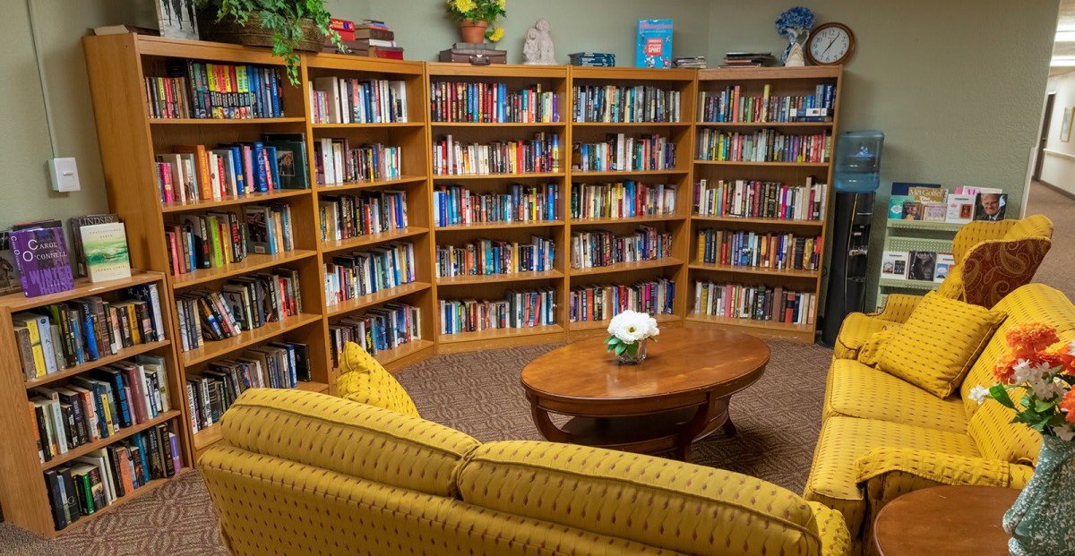 A cozy reading area with bookshelves filled with books, a yellow sofa, and a wooden coffee table.