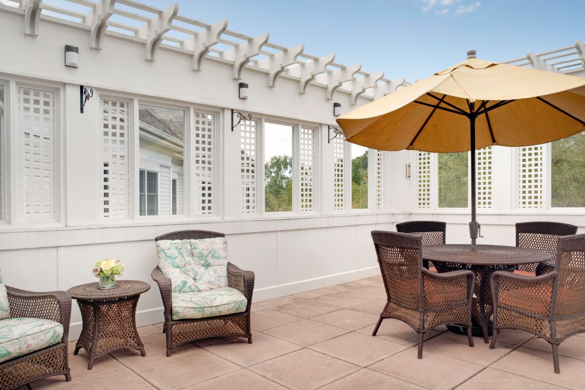 A stylish outdoor patio featuring wicker furniture and a large umbrella, perfect for relaxation.