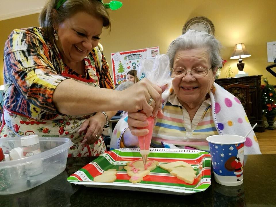 Two people decorating holiday cookies together, sharing smiles and joy.