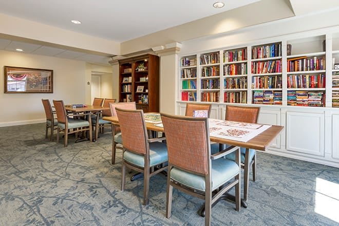 A cozy reading room with tables, chairs, and bookshelves filled with books.
