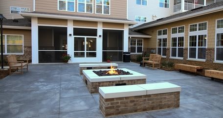 A modern outdoor courtyard featuring a central fire pit with surrounding seating.