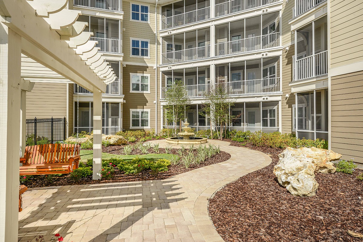 A beautifully landscaped courtyard in an apartment complex with a winding pathway and garden features.