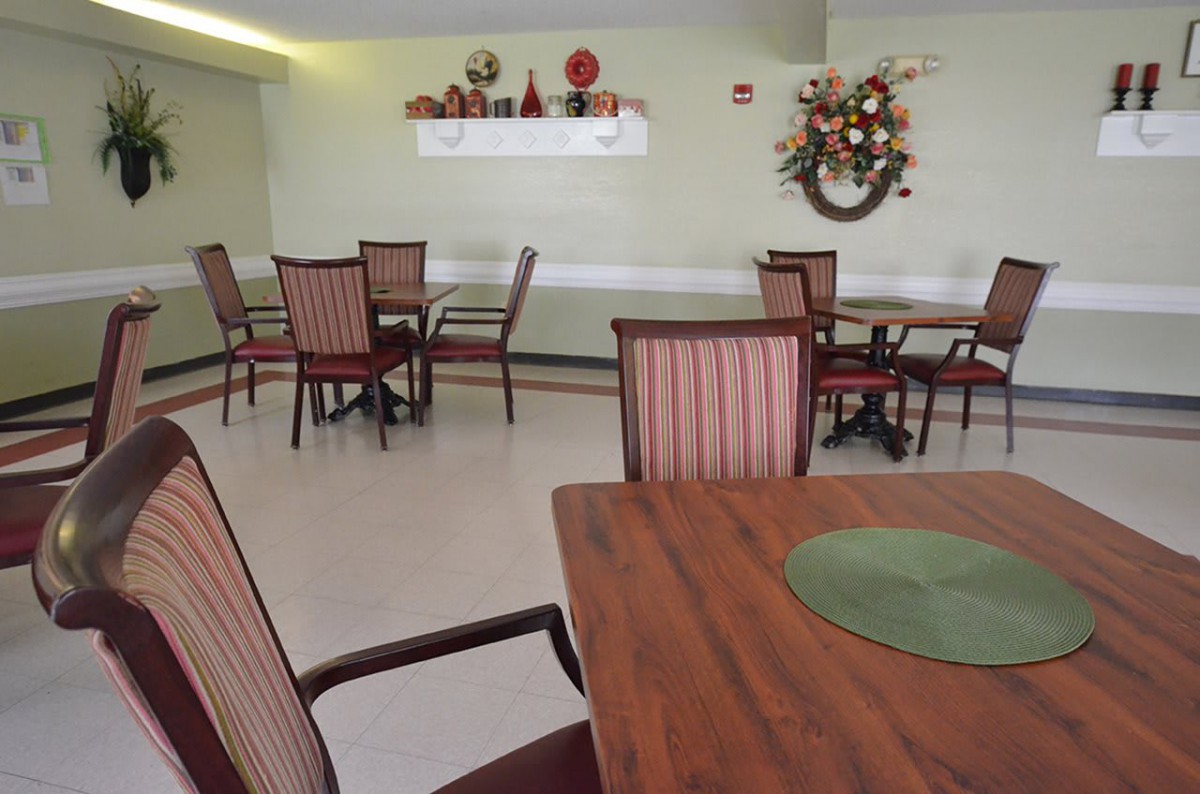 An indoor dining area with neatly arranged tables and chairs, decorated with wall art and ornaments.