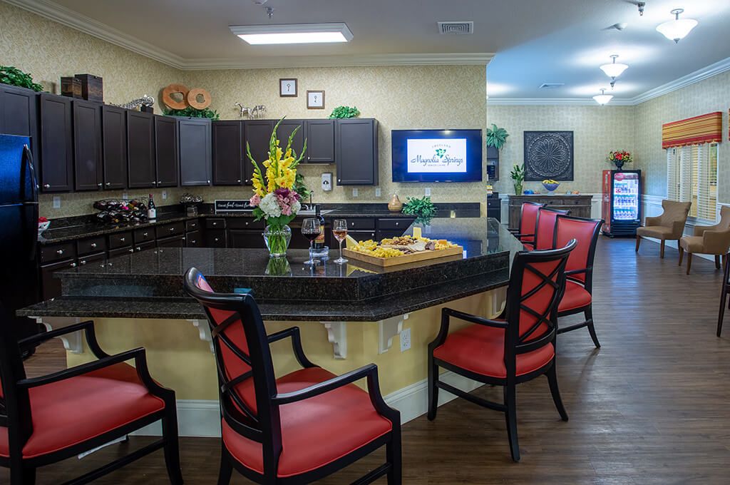 A cozy kitchen bar area with a granite countertop, featuring red-cushioned chairs and decorative elements.
