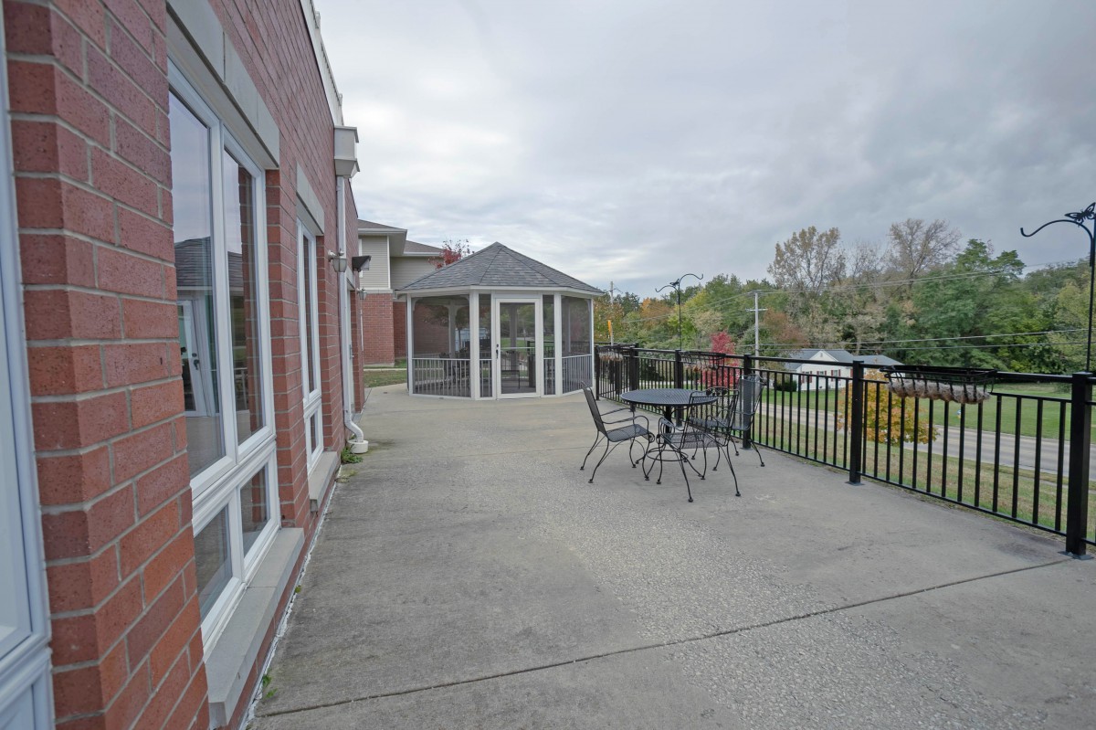 An outdoor patio with a table and chairs, adjacent to a building under an overcast sky.