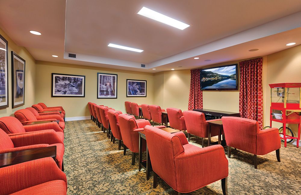 A cozy home theater room with red upholstered chairs and a large screen.