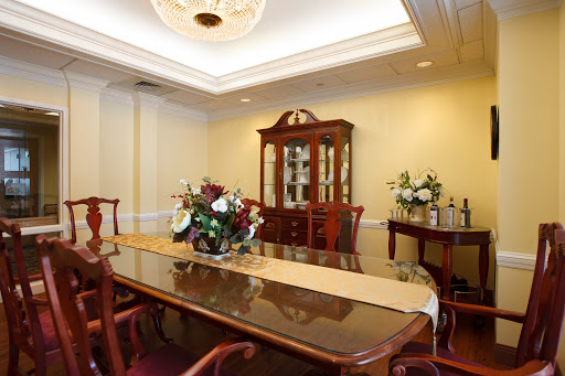 A beautifully designed dining room featuring a long table, elegant chairs, and a decorative cabinet filled with fine china.