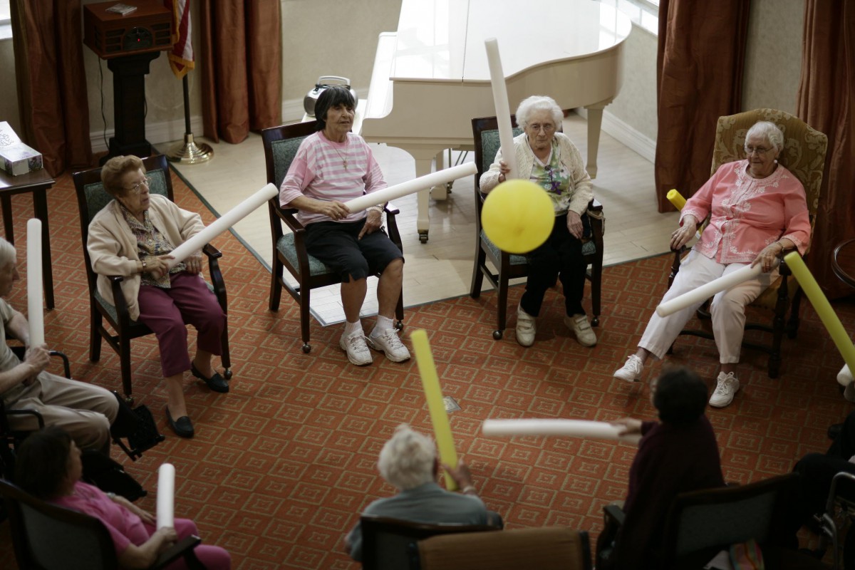 A group of seniors participating in a fun balloon game indoors.