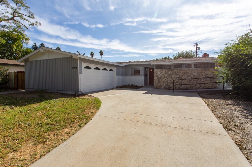 A view of a residential house with a driveway and clear sky.