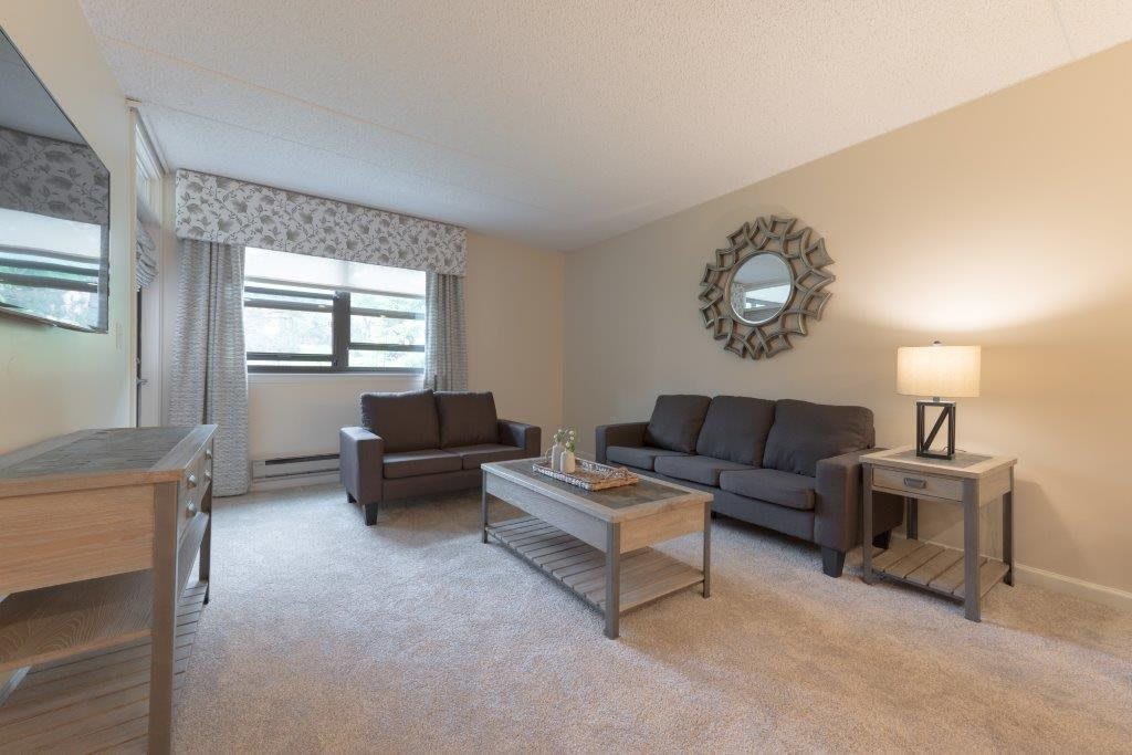A cozy living room with sofas and a coffee table, decorated with a mirror and a lamp.