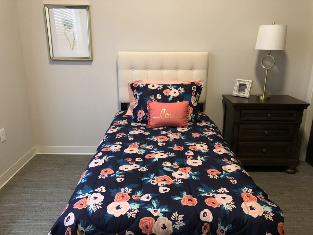 A neatly made single bed with floral bedding in a cozy bedroom.