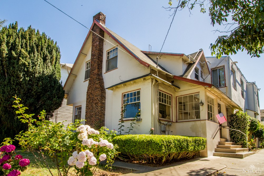 A charming residential house with a manicured garden on a sunny day.