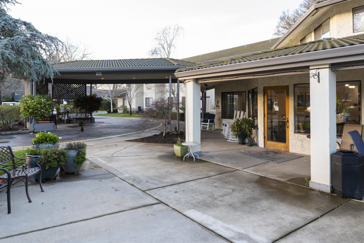 An exterior view of a building entrance with an awning and driveway.