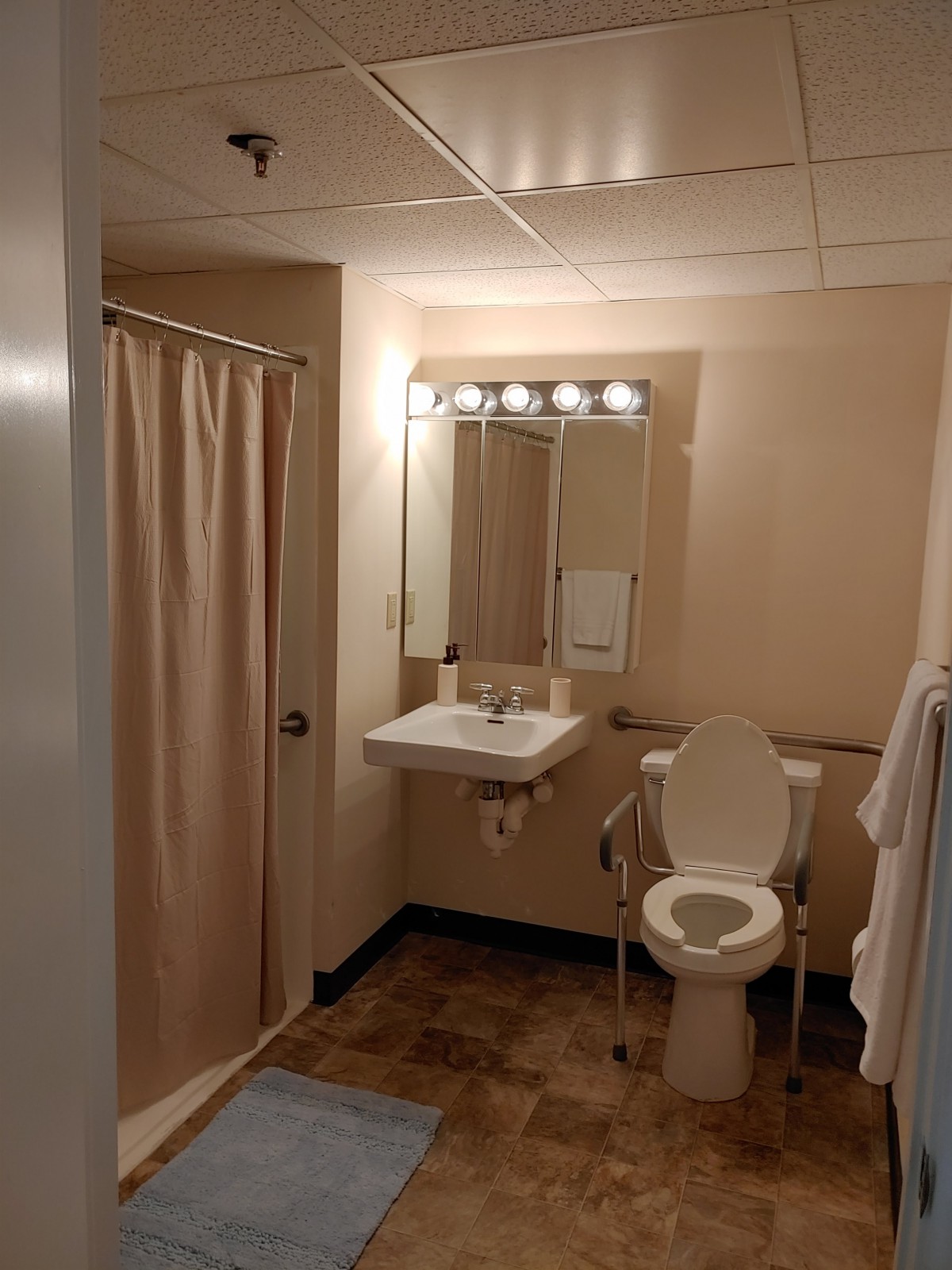 A well-lit bathroom with a toilet, sink, and shower area.