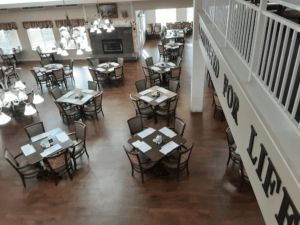 An empty restaurant dining area with neatly arranged tables and chairs on a wooden floor.